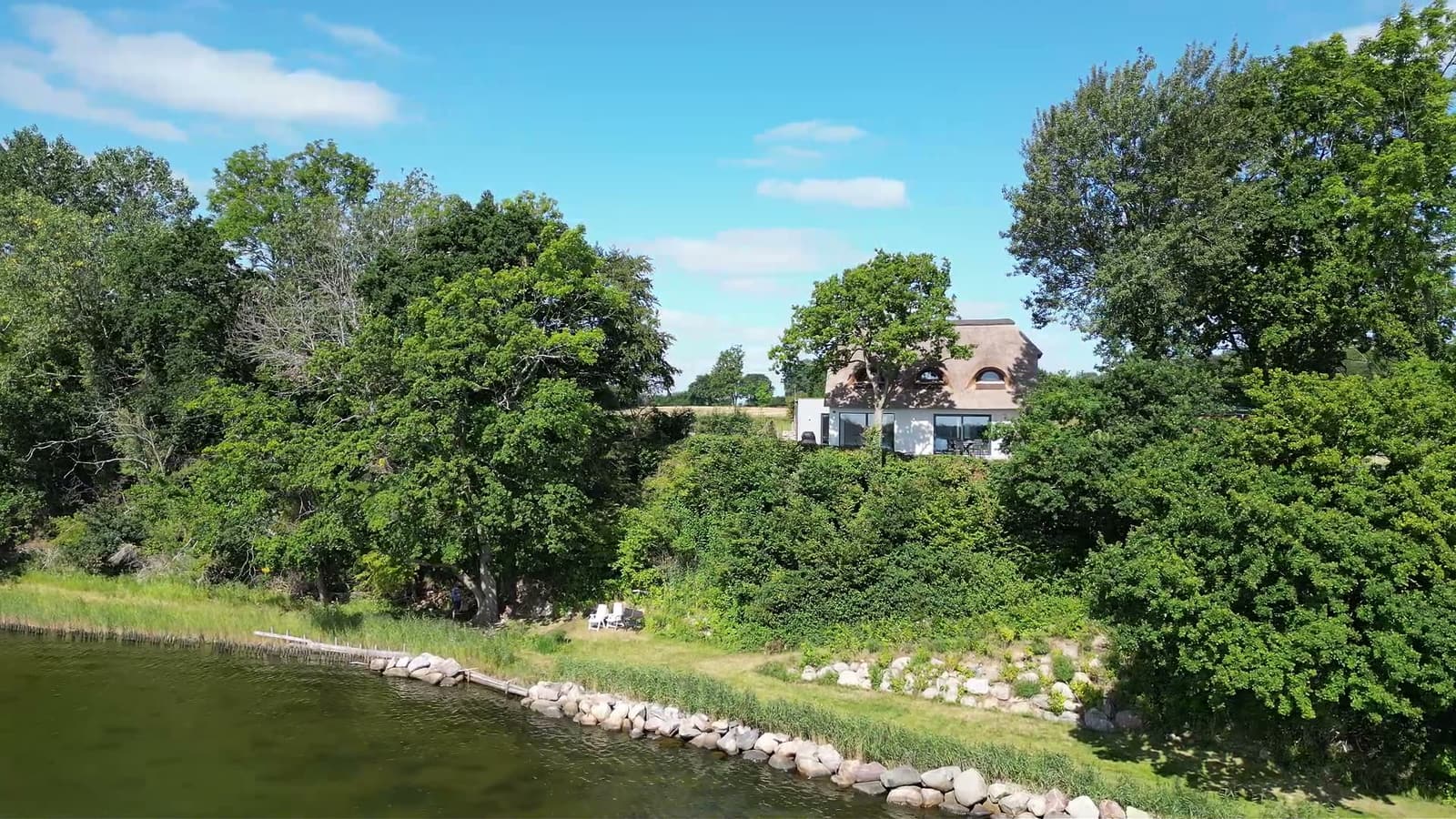 Aerial view of the thatched-roof house Karschau 11 and its private waterfront plot on the Schlei
