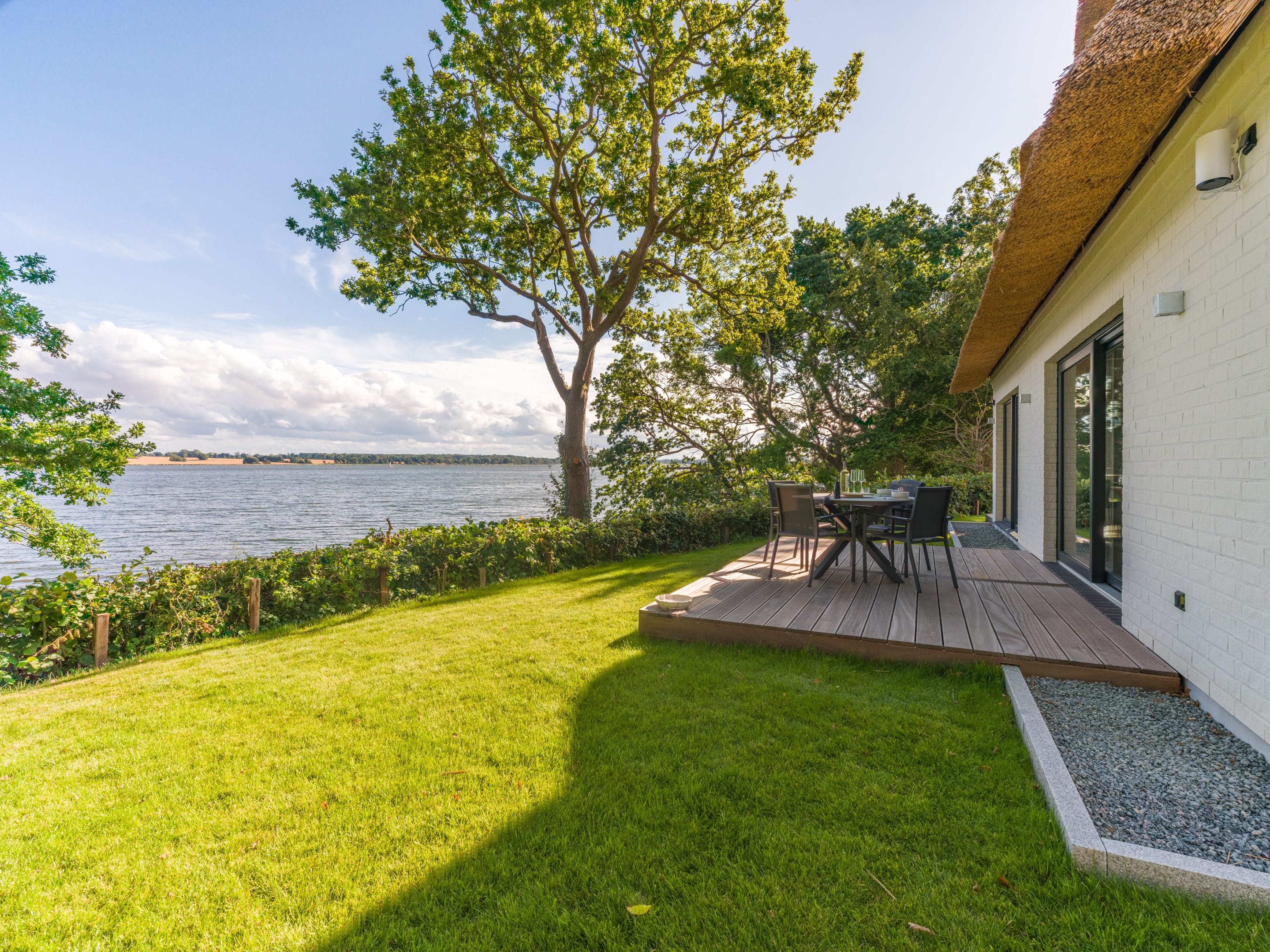 Holzterrasse am Wohnzimmer mit Rasen und Schleiblick