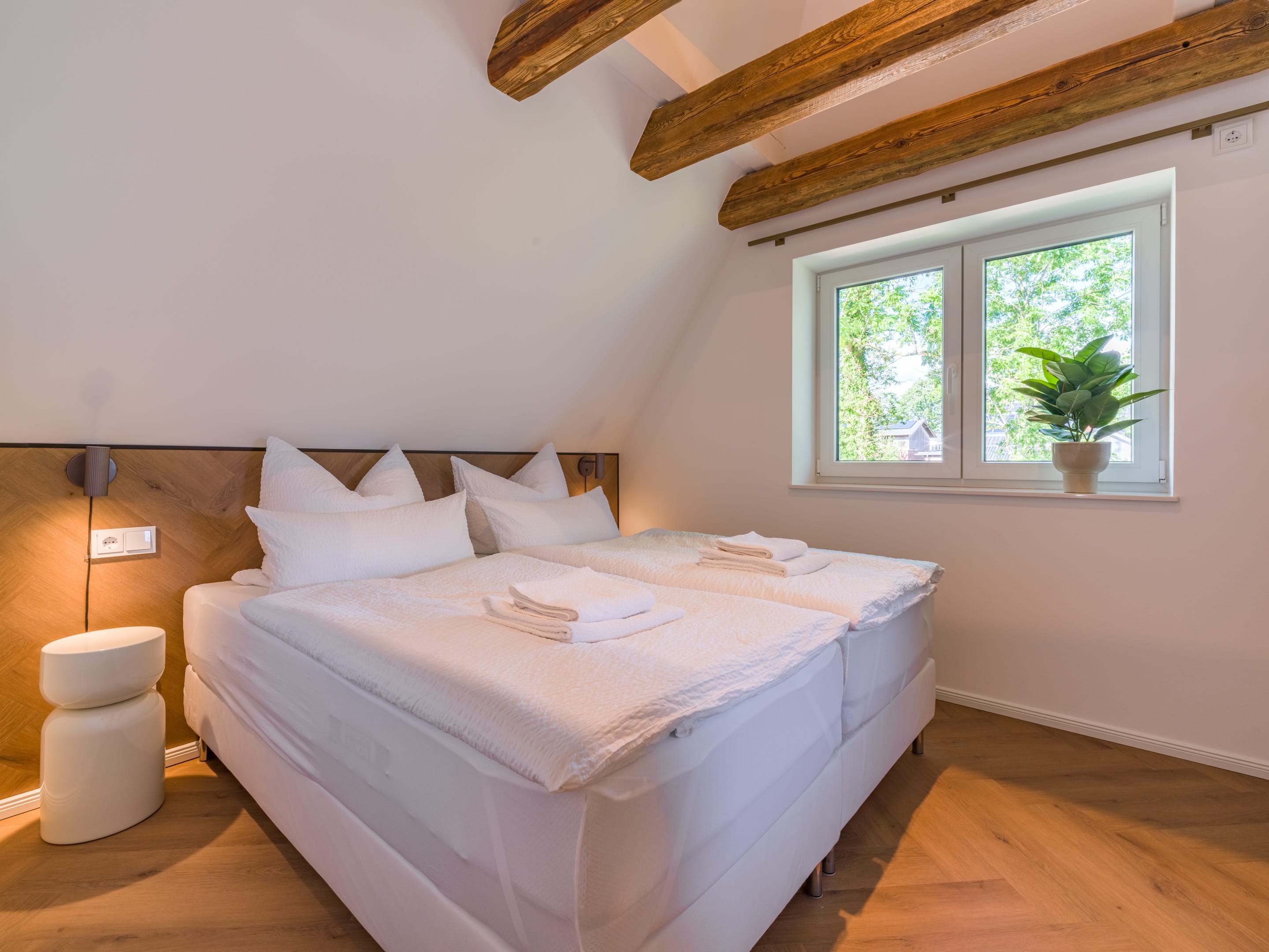 Bedroom with double bed beneath historic exposed ceiling beams