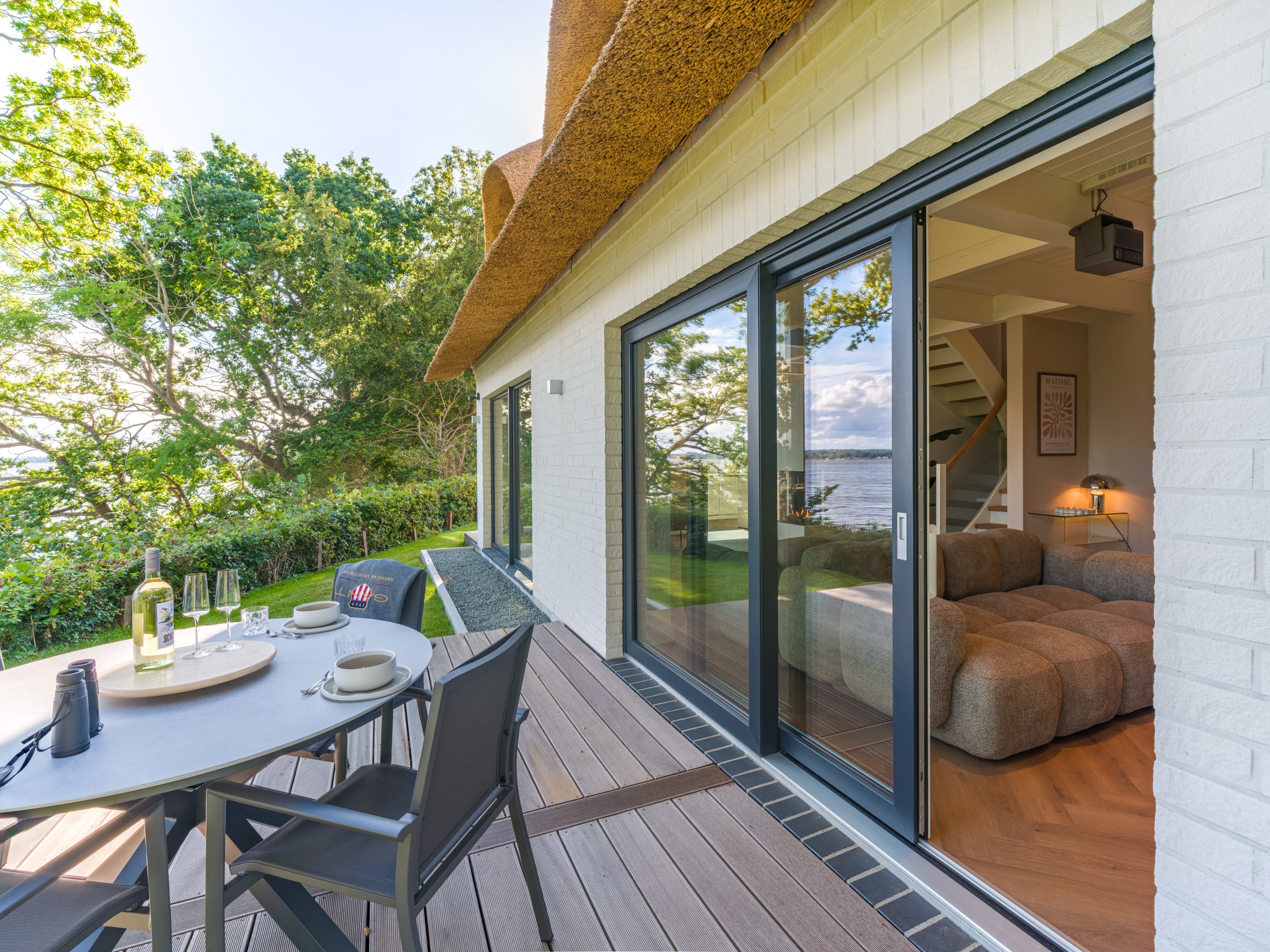 Laid table on the terrace beside the opened sliding door to the living area