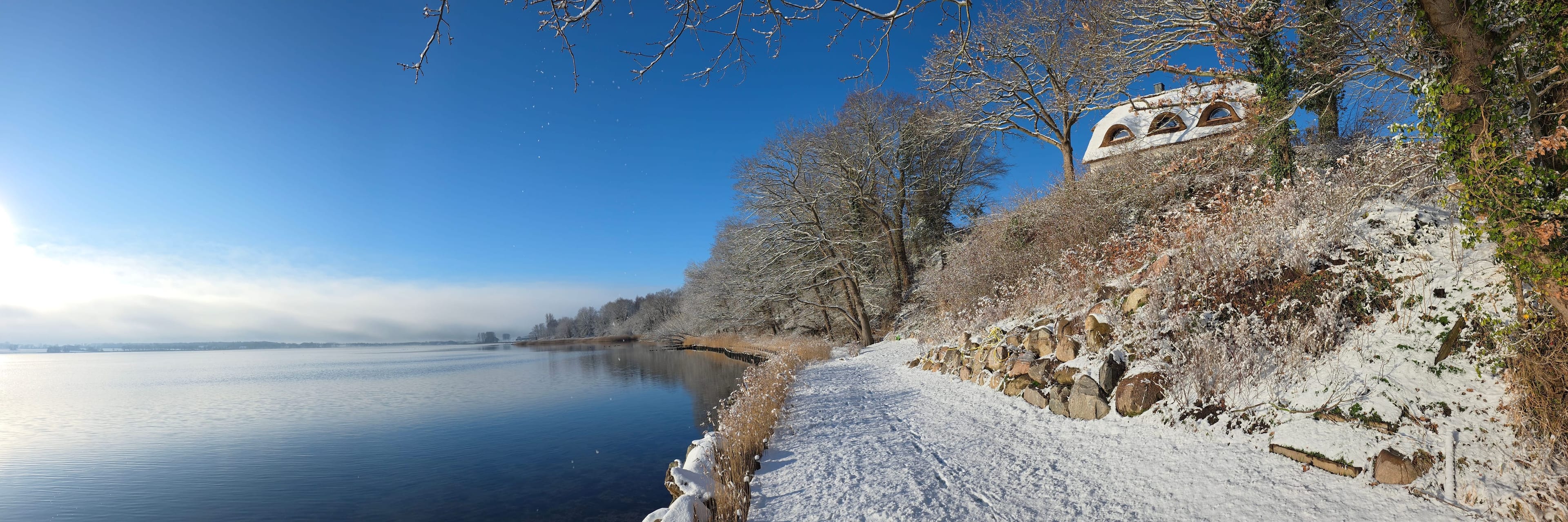 Verschneiter Uferweg an der Schlei im Winter, oben rechts das Reetdachhaus Karschau 11