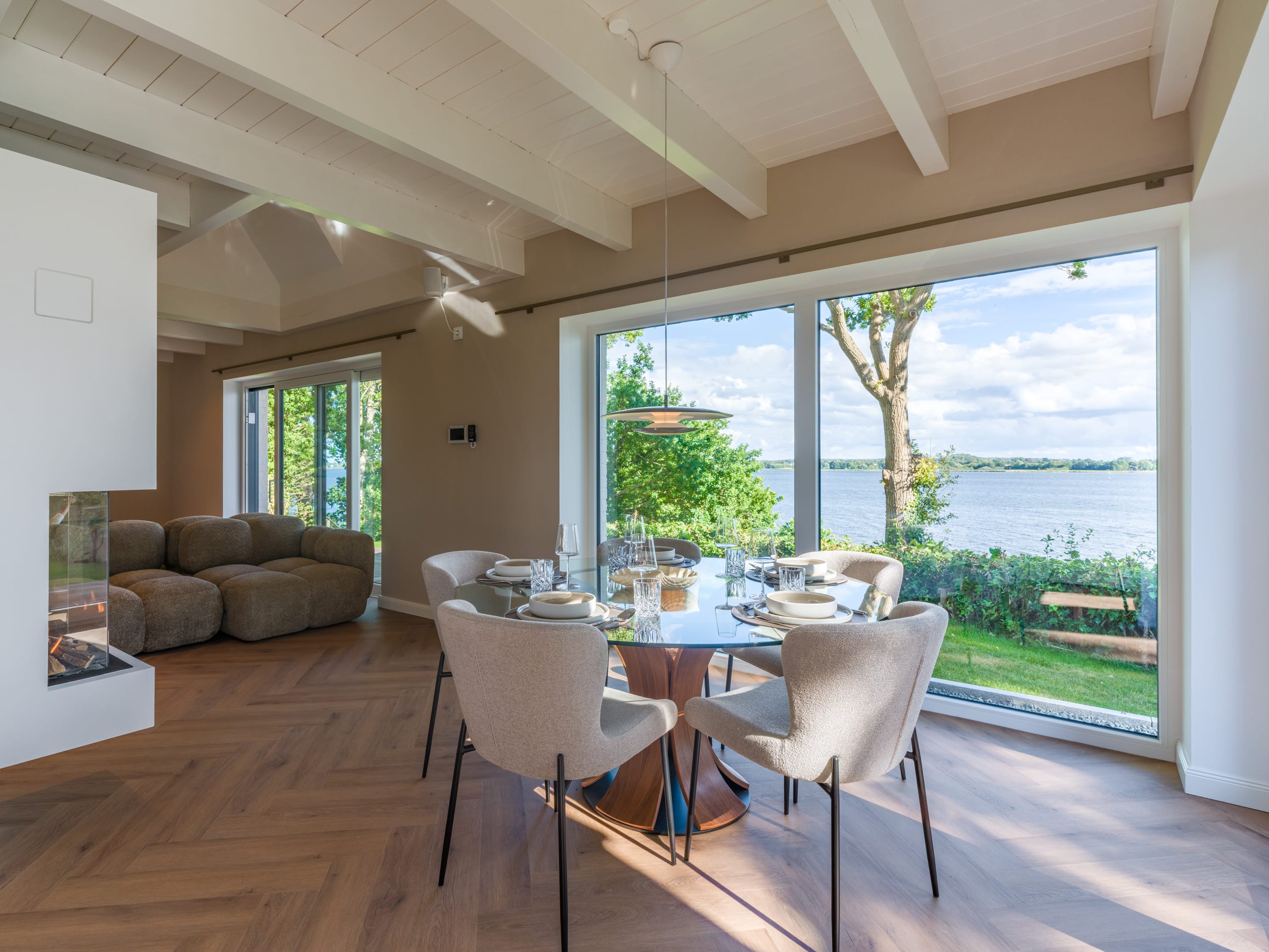 Open living and dining area with panoramic windows facing the Schlei